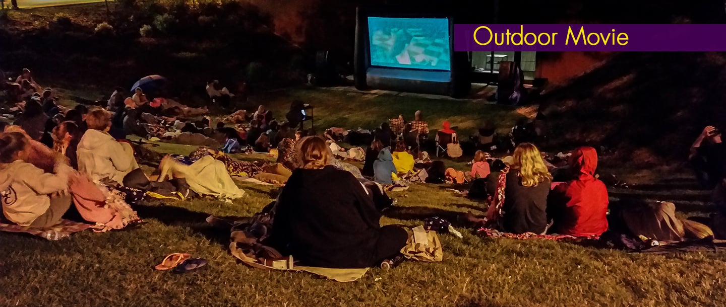 Students gathered outside on campus for the outdoor movie night event