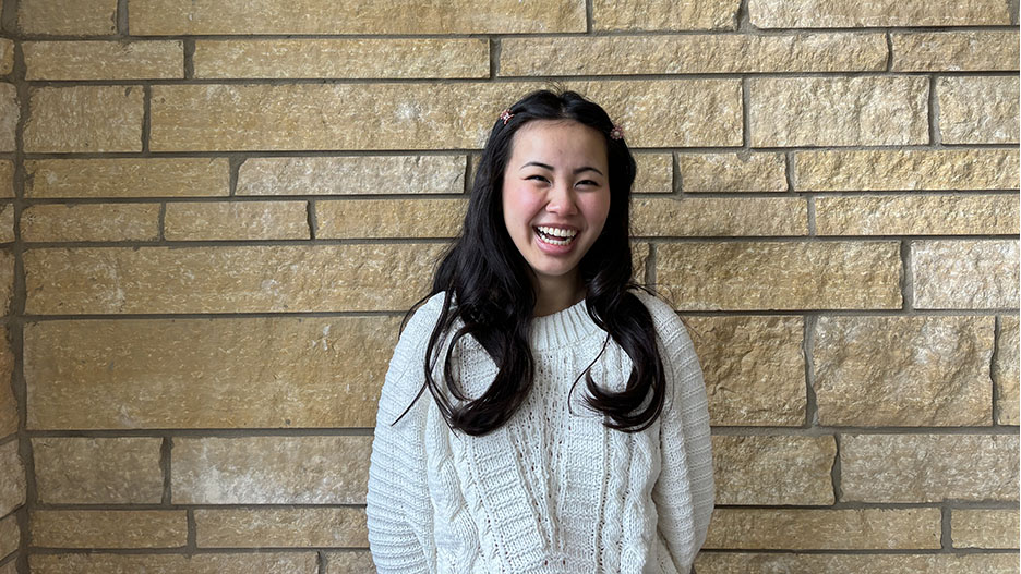 a person smiling in front of a brick wall