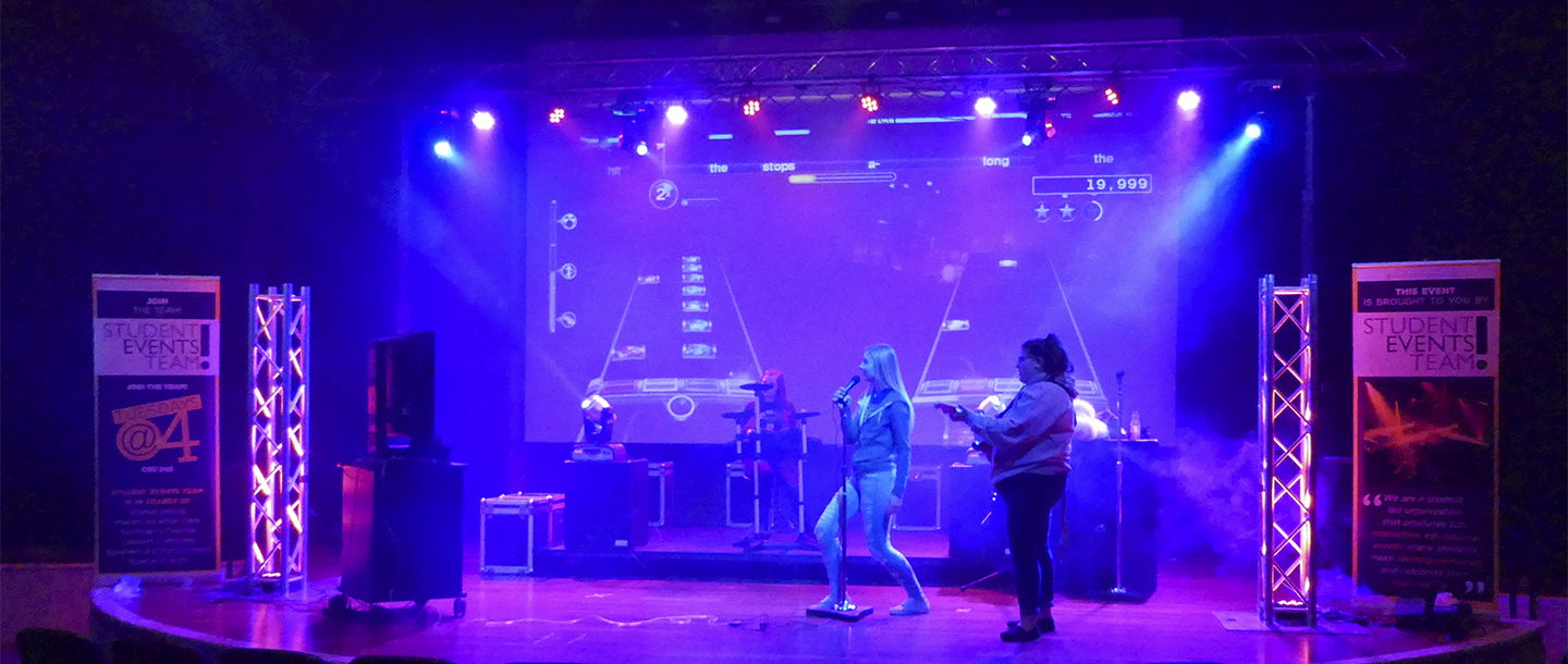 Students playing Guitar Hero and performing songs on stage