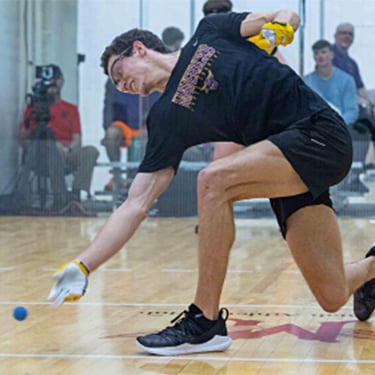 a person in a black shirt and shorts with a ball in his hand