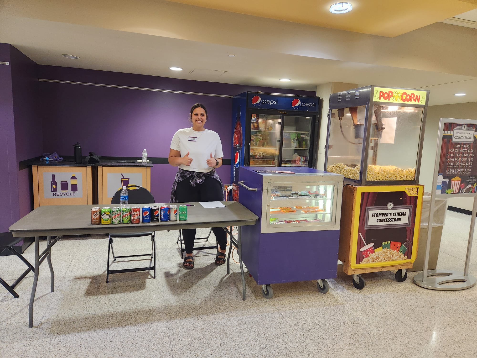 a person standing in front of a table with popcorn and soda cans