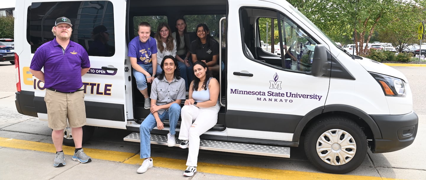 Maverick Electric Shuttle with students standing next to it