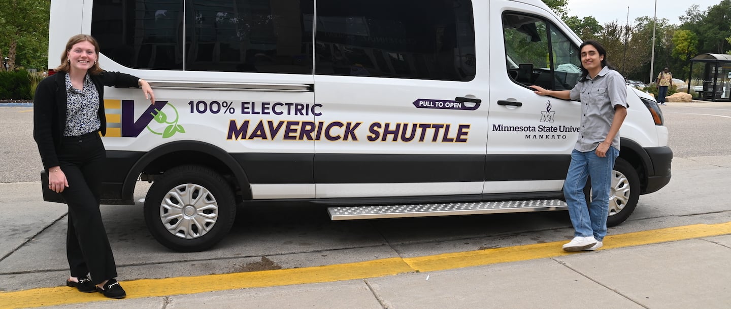 Maverick Electric Shuttle with students standing next to it