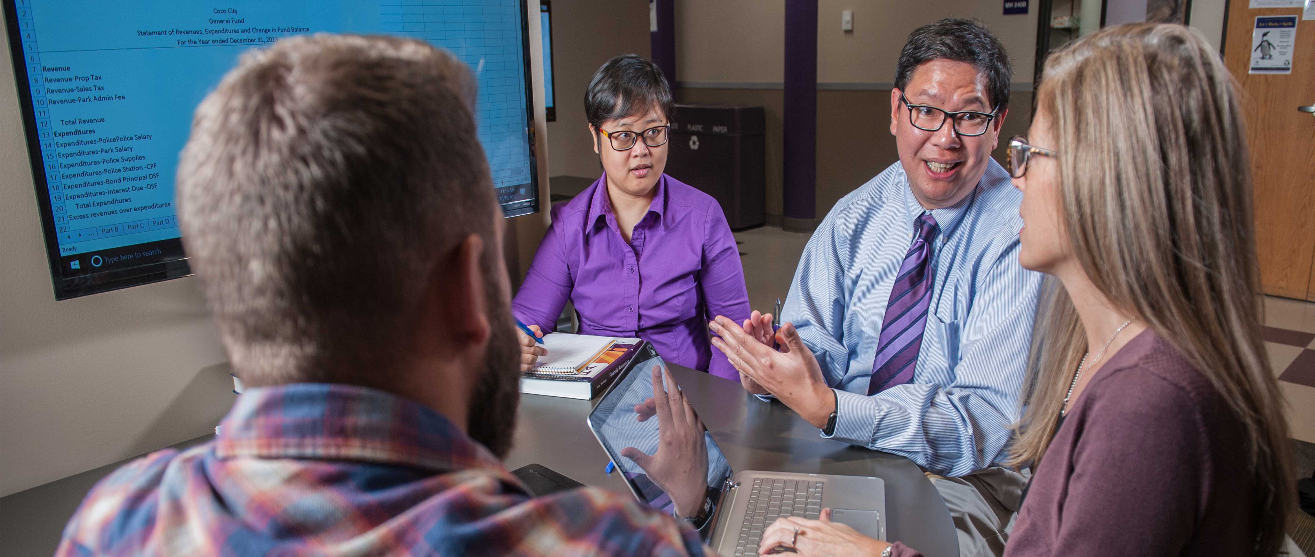 an instructor sitting down at a table with a group of students