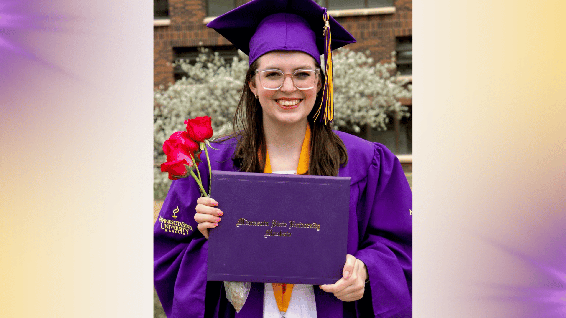 a person in a graduation gown holding a diploma and flowers