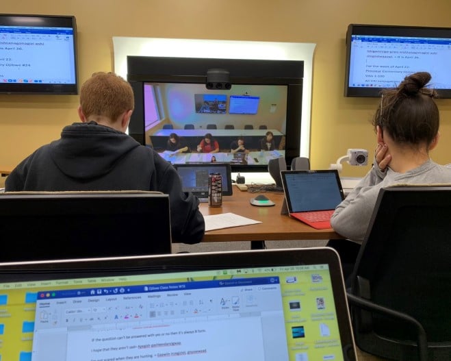 a group of people sitting at a table with computers