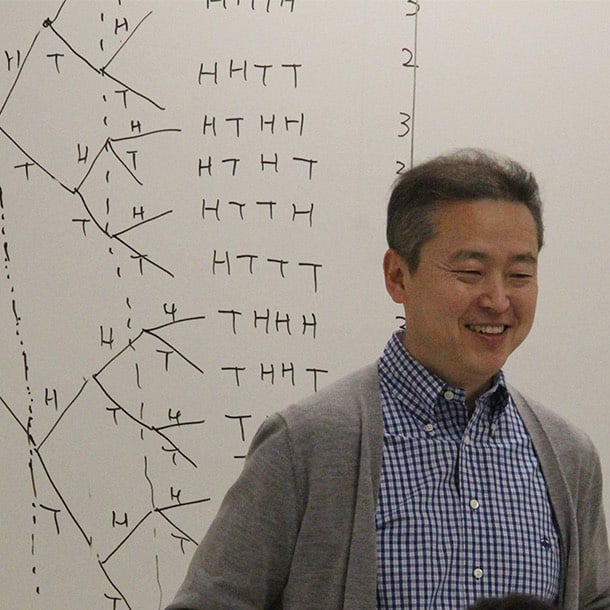 a person smiling in front of a whiteboard