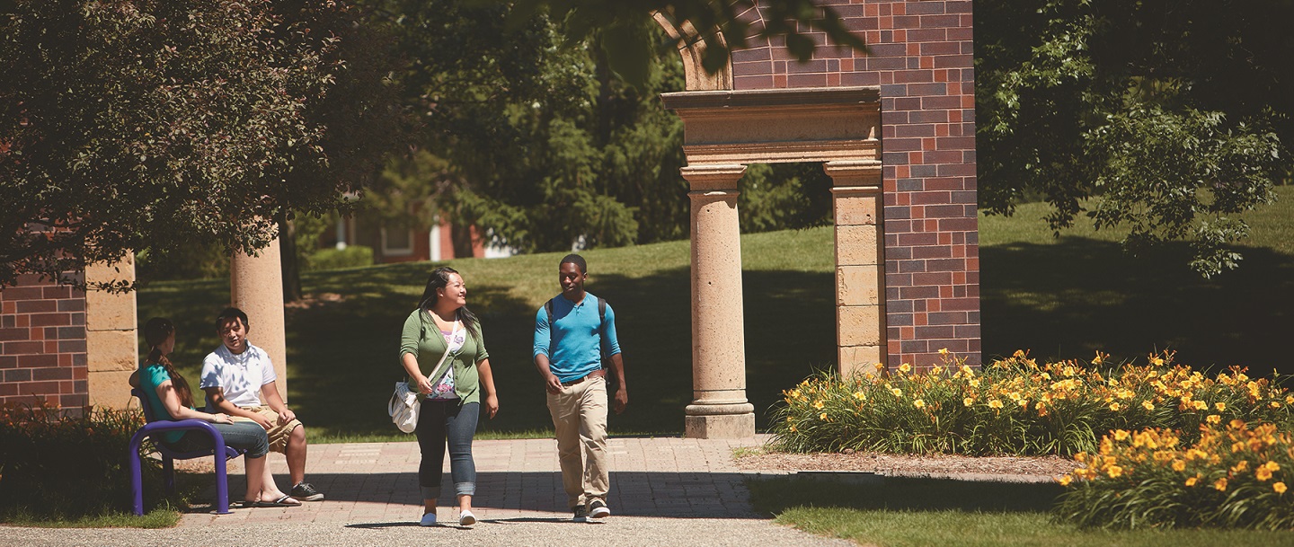 students walking on campus with the arch in the background