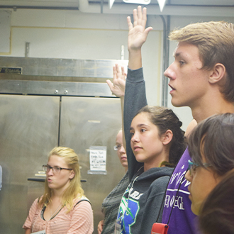 students raising hands to answer a question