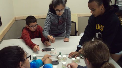 ETS students building something with string and dixie cups