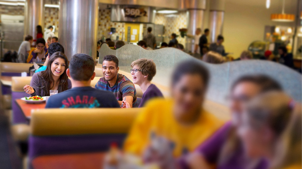 Students sitting in a booth at the Dining Center eating and Laughing