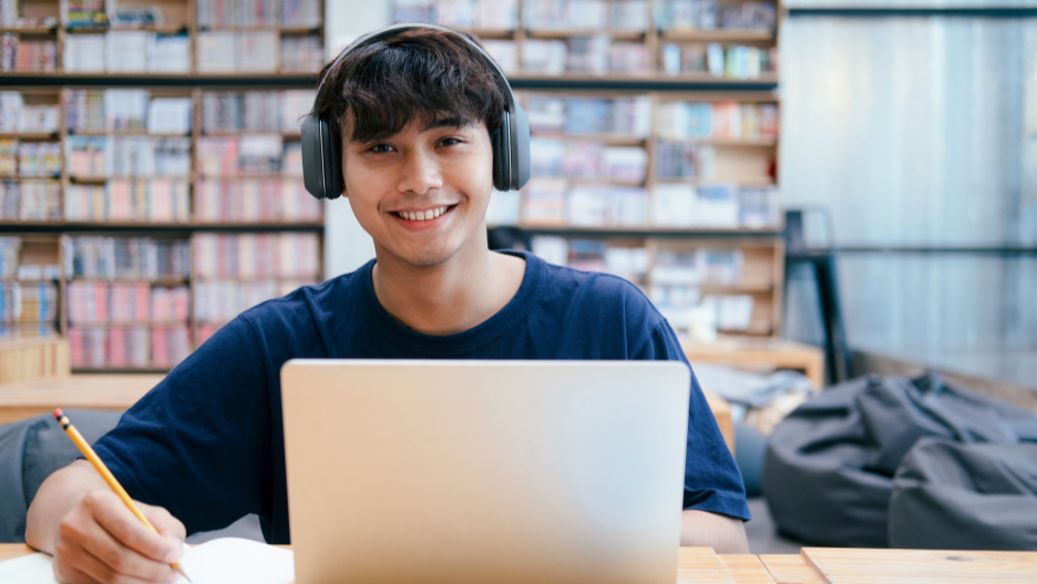 a person wearing headphones and sitting at a table with a laptop