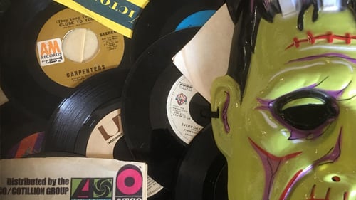 Closeup of scattered records, newspapers and a Frankenstein mask 